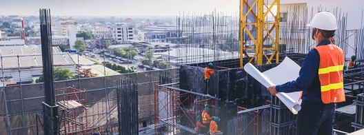 Engineer in hardhat and safety vest overseeing the construction of a building