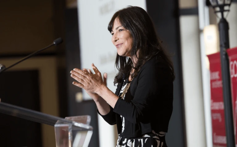Woman clapping at podium while delivering speech at Bradley University